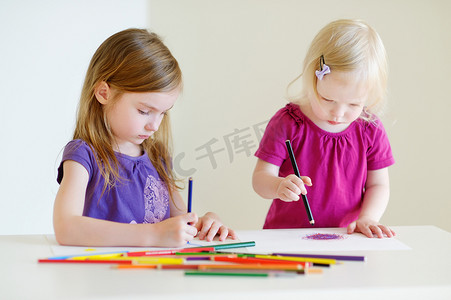 两个小姐妹用彩色铅笔画画
