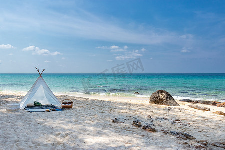 白色沙滩上浪漫的白色野餐帐篷，背景是清澈的海水和蓝天