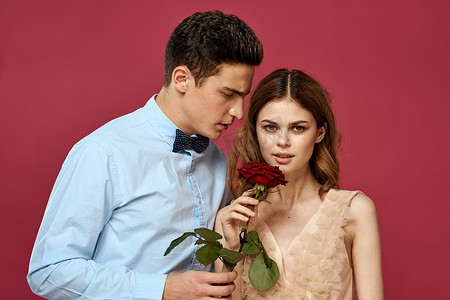浪漫情侣的肖像，爱上孤立背景中的红玫瑰和经典西装晚礼服