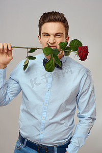 浪漫的男人，一朵红玫瑰，穿着蓝色衬衫，脖子上系着领结，灰色背景