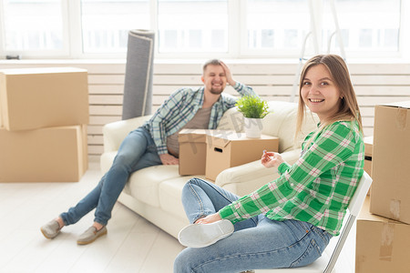 积极开朗摄影照片_积极开朗的夫妇很高兴能带着他们的财物搬到客厅里的新公寓。
