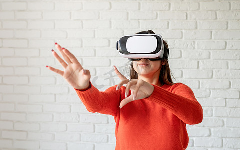 微笑快乐的女人在家里使用虚拟现实 VR 耳机眼镜获得经验，多用手势