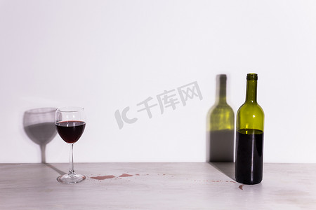 瓶子里装着酒和玻璃，桌子上有红色的酒水坑。