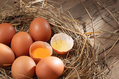 生鲜邮报摄影照片_木质背景上的干草窝里有几个生鲜鸡蛋