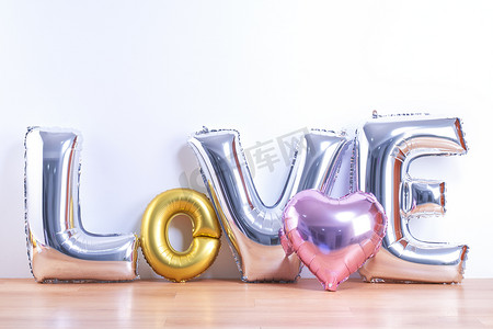 情人节，母亲节设计理念 — 美丽的气球，在浅色木地板和白墙背景上，有爱字形状，特写。