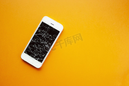 碎屏摄影照片_橙色背景中智能手机的碎屏
