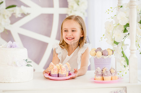 小女孩拿着一个粉色盘子，糖果吧里放着甜蛋糕