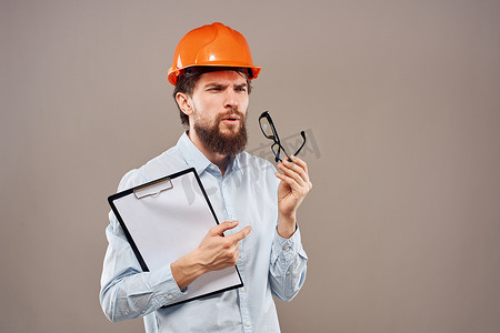 一个身穿橙色油漆的男子，手里拿着文件，正在建设一家工业企业