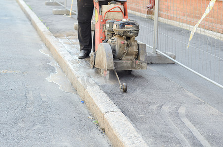 道路工人切割柏油路，从事道路重建工作。