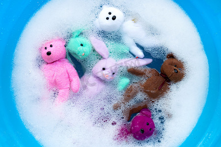 夹娃娃摄影照片_将带熊玩具的兔子娃娃用洗衣液水浸泡