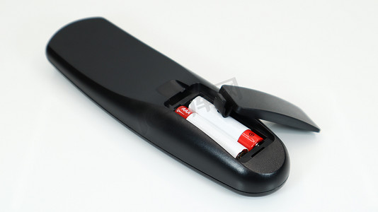 黑色电视遥控器，白色背景上配有红色和白色的 AAA 碱性电池。