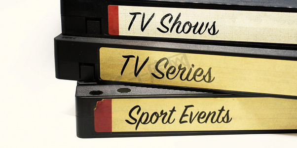 标明摄影照片_VHS 磁带堆叠在一起，标签上标明录制在磁带上的各种电视娱乐节目。