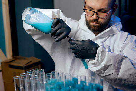蓝色疫苗摄影照片_一位身穿防护服、装有蓝色疫苗液的男科学家