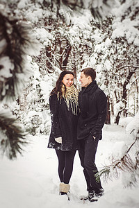 冬天总结摄影照片_一个男孩和一个女孩穿着温暖的衣服和围巾在雪天散步