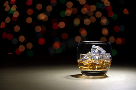 民国酒馆摄影照片_散景背景的金色表面玻璃杯中的苏格兰威士忌