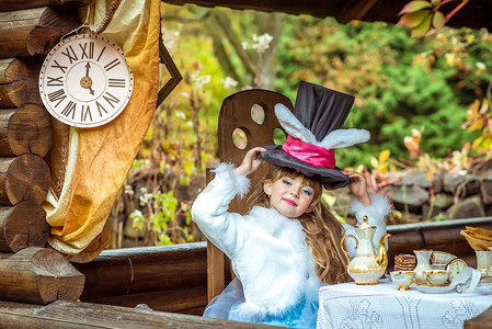 一个漂亮的小女孩在桌子上头顶着耳朵像兔子一样的圆筒帽