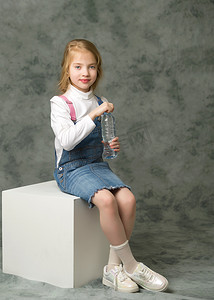 女性喝水摄影照片_小女孩用塑料瓶喝水。
