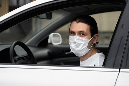 为了保护自己免受细菌和病毒侵害，戴着防护口罩的男子正计划开车。
