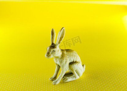 黄色背景中兔子的塑料雕像