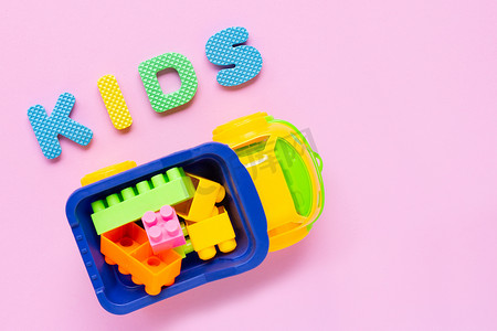 五颜六色的儿童玩具，在粉红色的背景上带有字母“KIDS”。