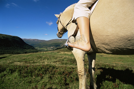 女子骑马摄影照片_乡村环境中骑马的年轻女子