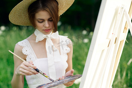 女艺术家在户外的画架上画一幅画