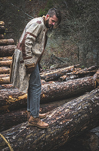 鞋子男孩摄影照片_年轻人在森林里的原木上。