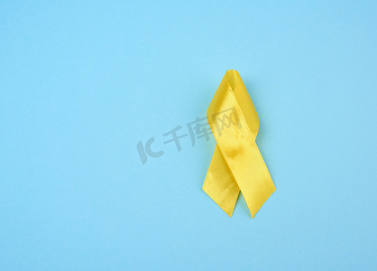 黄色丝带摄影照片_蓝色背景中 petoi 形的丝绸黄色丝带