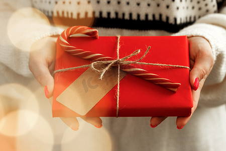 茶叶包装包装盒摄影照片_穿毛衣的女手拿着包装好的圣诞礼物