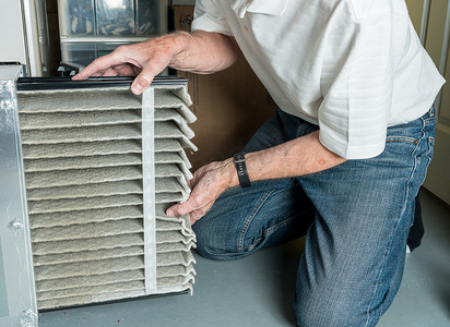 家庭暖通摄影照片_更换 HVAC 炉中脏空气过滤器的高级人员