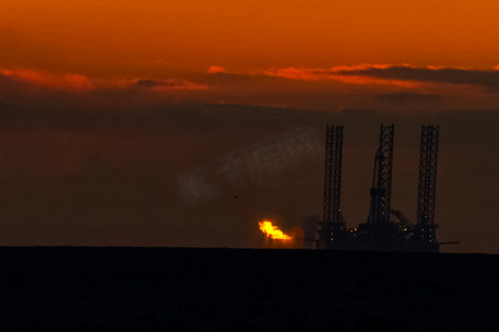 在日落时的石油平台与燃烧的火炬。石油平台的牵引。