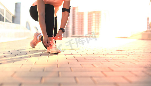 年轻健身漂亮的运动女跑步者把鞋带系在运动鞋上，准备跑步