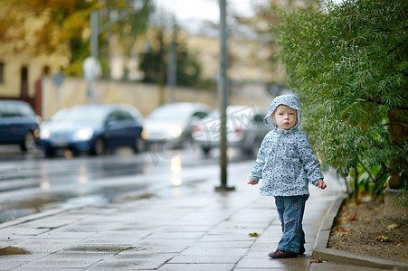 可爱的蹒跚学步的女孩在雨天