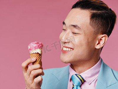 穿着经典西装和冰淇淋的快乐男人在锥形粉红色背景中