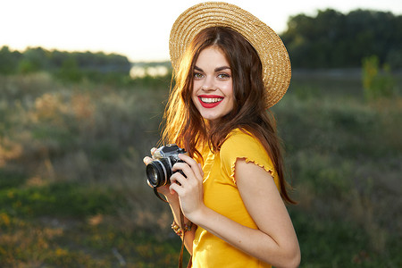 手拿相机的女摄影师微笑红唇帽黄色T恤夏季自然