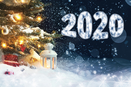 2020灯光摄影照片_圣诞卡 — 圣诞树下雪地里的礼物和灯笼，装饰着灯光和圣诞装饰，并题词 2020