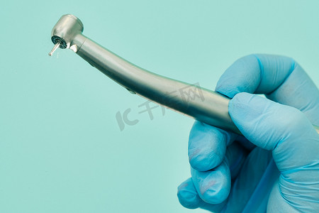 戴牙套摄影照片_牙科诊所里戴着手套的牙医在工作前拿着工具
