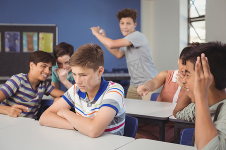 学校朋友在教室里欺负一个悲伤的男孩