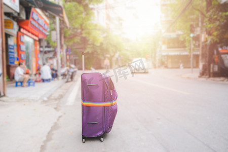 飞行旗摄影照片_大花旗街头的紫色行李带或手提箱
