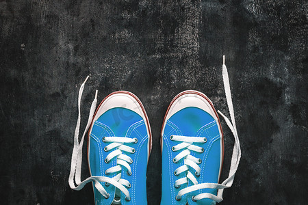 蓝色-青色-绿色-绿松石色运动鞋，深色混凝土背景上系着不系带的鞋带。