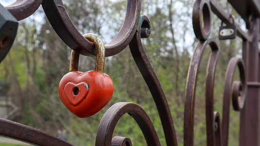 红色爱心上的钥匙摄影照片_桥上的红色挂锁金属爱心形锁。
