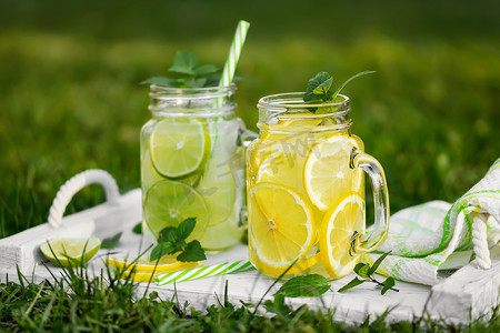 夏日草坪上的梅森罐子里放着清凉的自制柠檬水，里面有薄荷、柠檬和酸橙