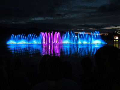 夜晚，蓝色和深红色的喷泉洒在水面上。