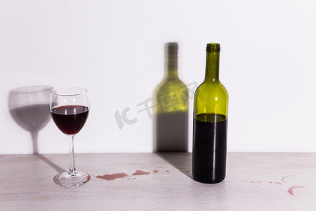 瓶子里装着酒和玻璃，桌子上有红色的酒水坑。