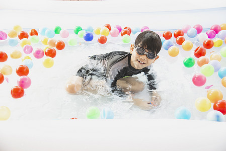 男孩在小游泳池玩具中玩彩球 — 水池玩具概念中的快乐男孩