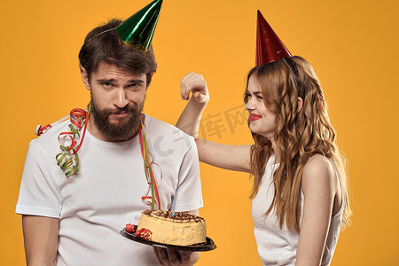 男女生日喜庆蛋糕黄色背景和头上的帽子