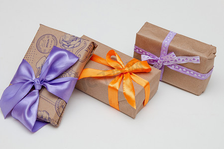 白色背景盒子里的礼物复制顶视图金色丝带，蝴蝶结包裹着棕色纸紫色丝带辫子