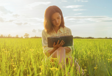 读书的女人摄影照片_在夏季草地上读书的女人