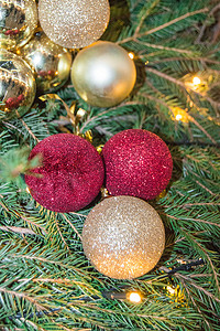 天然冷杉树枝背景上可爱的圣诞闪闪发光的红色和金色玻璃球，正宗的圣诞背景，有冷杉树枝和装饰，垂直框架