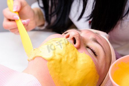 洁面后，在脸上敷上金色面膜，芳香面膜可滋润、焕活和提亮肌肤。